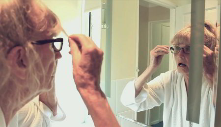 An older woman with dementia looking at herself in the mirror