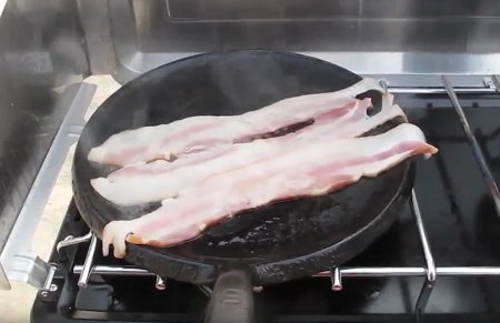 Fatty bacon frying in a skillet